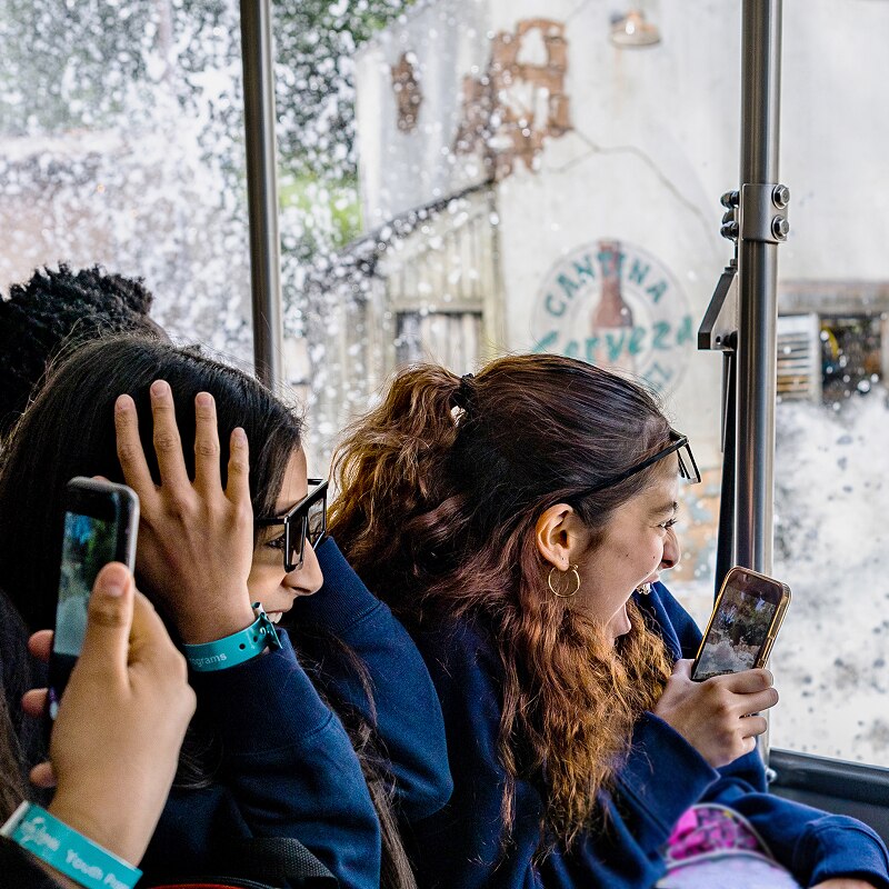 Group of thrilled passengers on the Studio Tour attraction, with the shark from Jaws passing by and spraying water on them