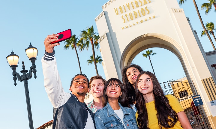 Group of teens taking a selfie in front of the Universal Studios Hollywood entrance