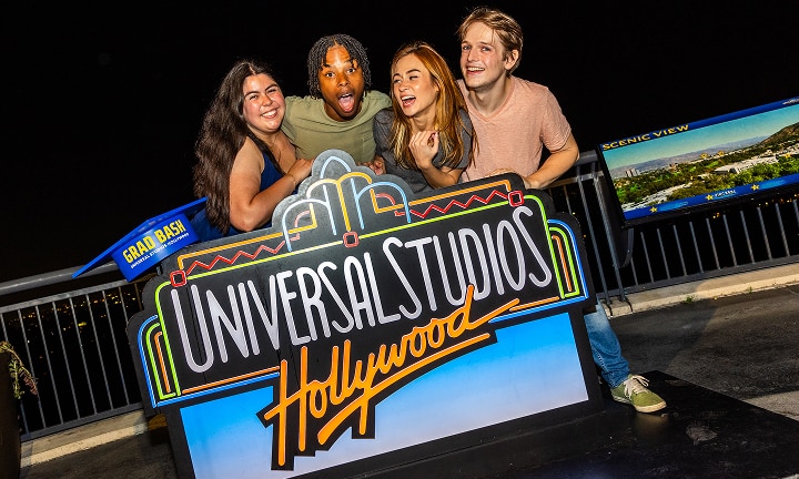 Group of teens posing for a photo behind a Universal Studios Hollywood Grad Bash sign