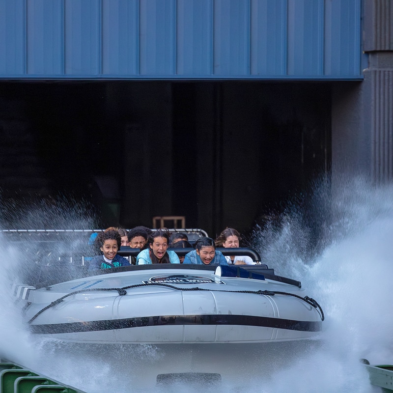Boat full of riders splashing down at the end of the drop on Jurassic World - The Ride