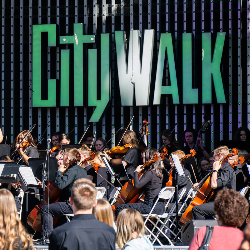 An orchestra comprised of students performing on the CityWalk stage