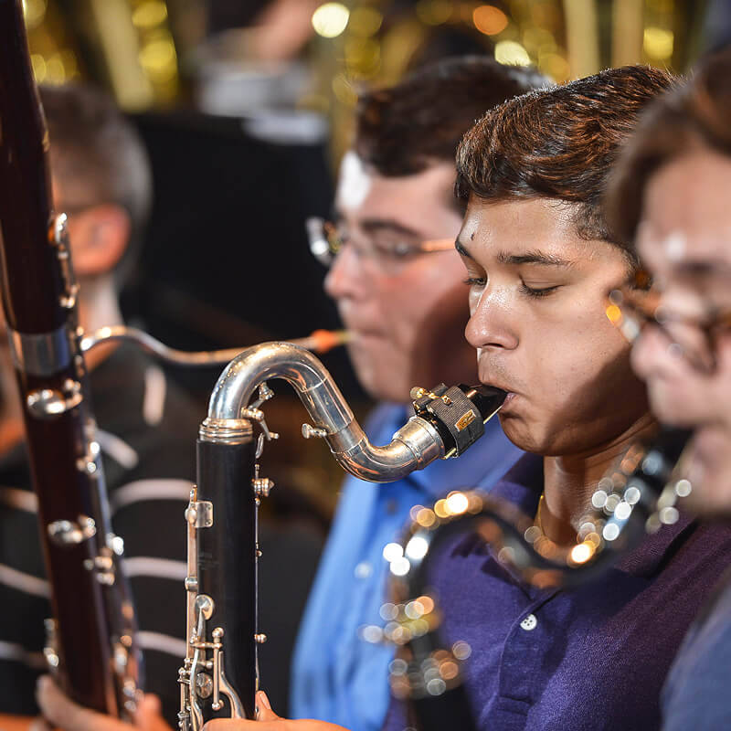 Close-up shot of students at a performance playing woodwind instruments