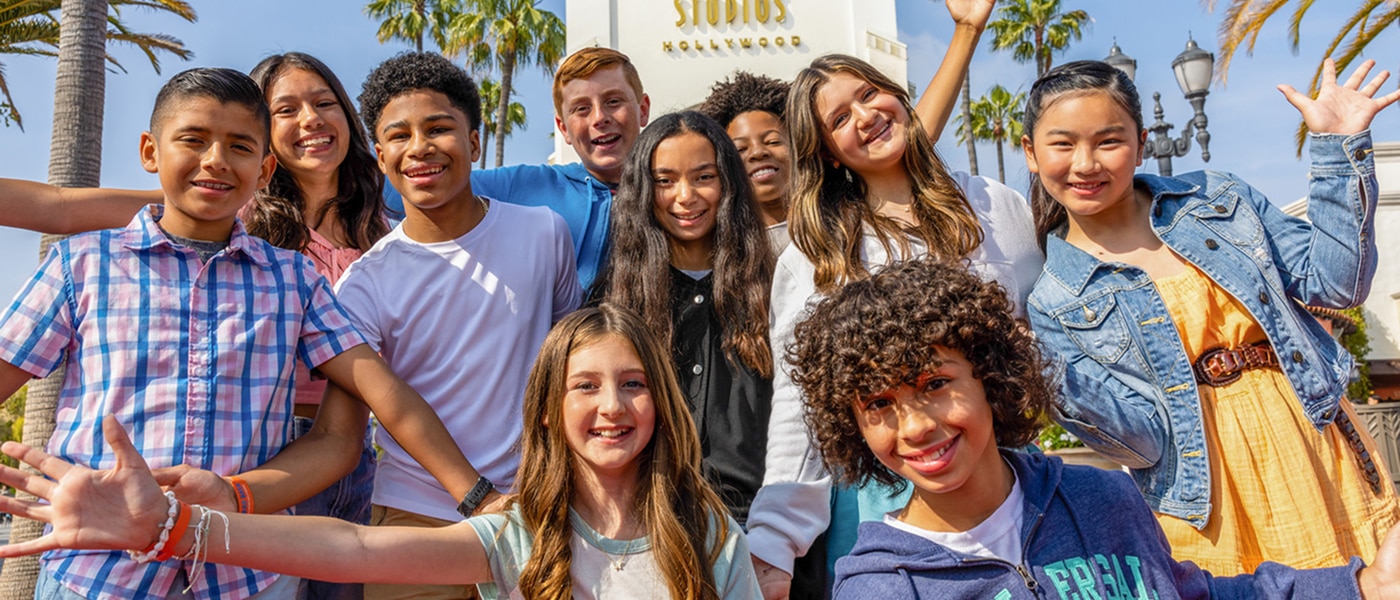 Group of young students smiling in front of the Universal Studios Hollywood entryway arch