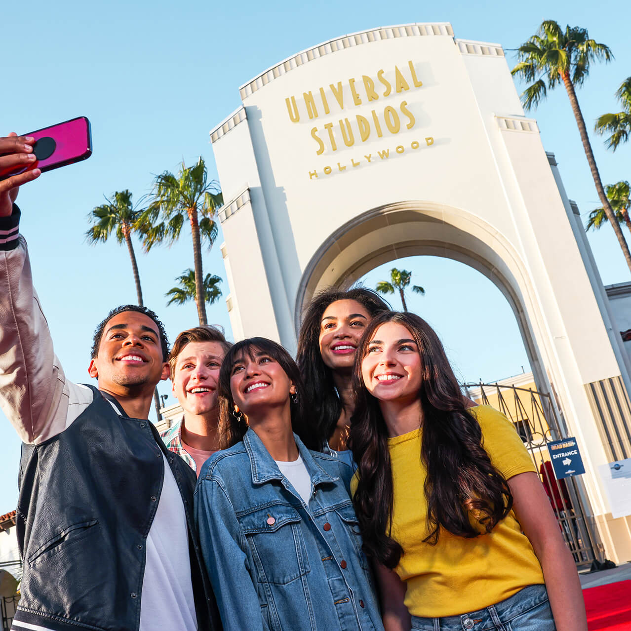 People taking a selfie in front of the Universal Studios Hollywood Entrance Sign