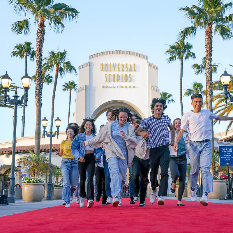 People walking a red carpet in front of the Universal Studios Hollywood entrance sign