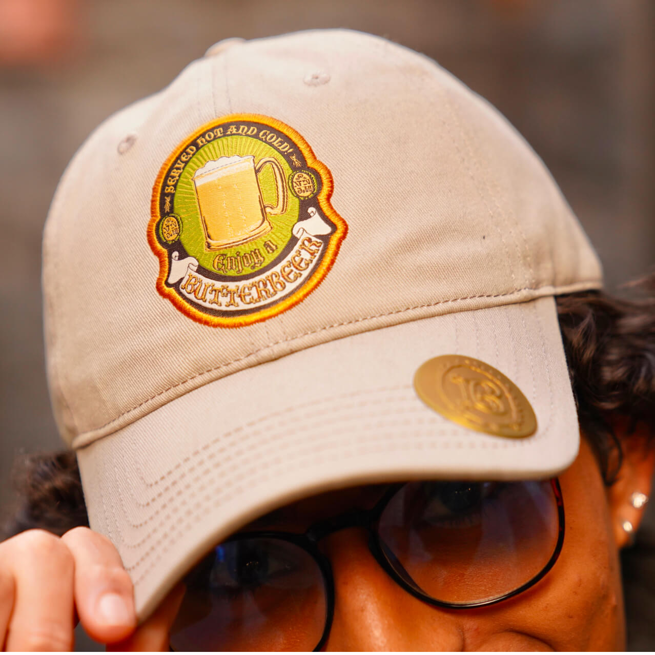 Up-close shot of a man holding the edge of his Butterbeer™ hat.