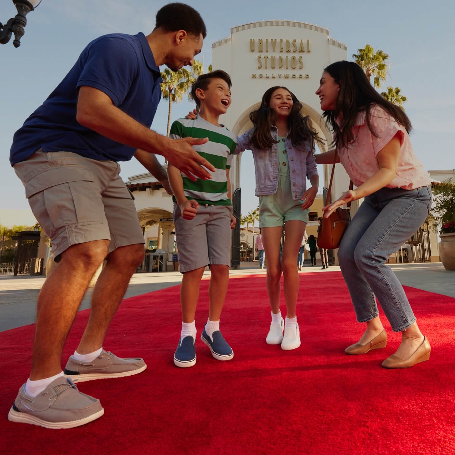 Family smiles and huddles on the red carpet in front of the Universal Studios Hollywood arch.