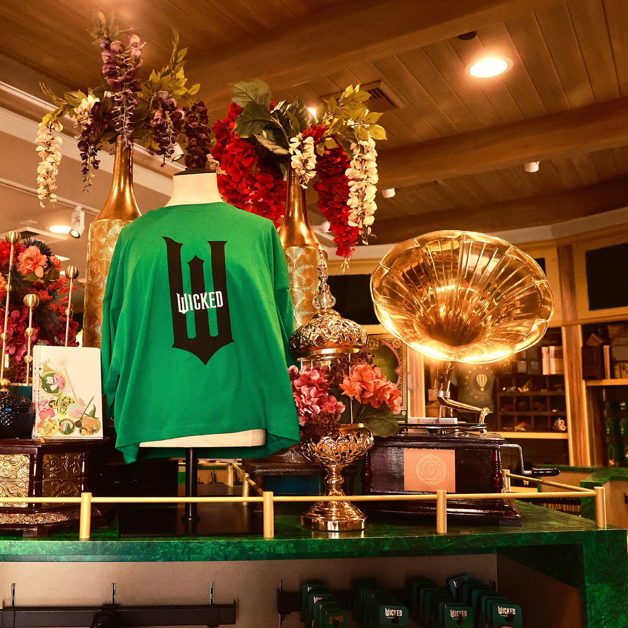 A Wicked t-shirt surrounded by flowers and a gramophone inside the Feature Presentation Store at Universal Studios Hollywood.