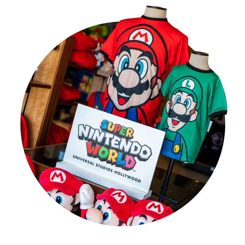 Super Nintendo World merchandise in a store at Universal Studios Hollywood featuring Mario Brothers t-shirts and plush toys.