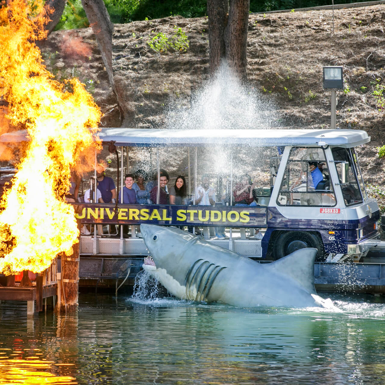 Guests aboard a tram on the Universal Studios Hollywood Studio Tour gaze at a blazing fire from the “Jaws” set.