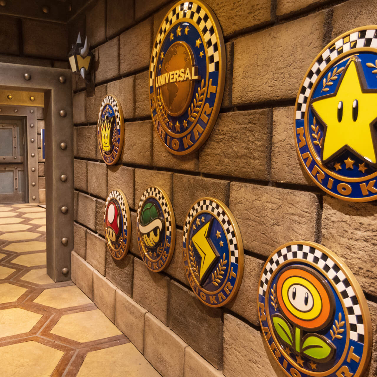 A hallway in Bowser’s Castle is decorated with round medallions each representing a different race in the Mario Kart ride.