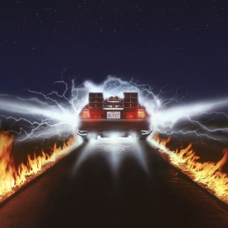 The Time Machine from Back to the Future speeding away from camera with a trail of fire and electricity.