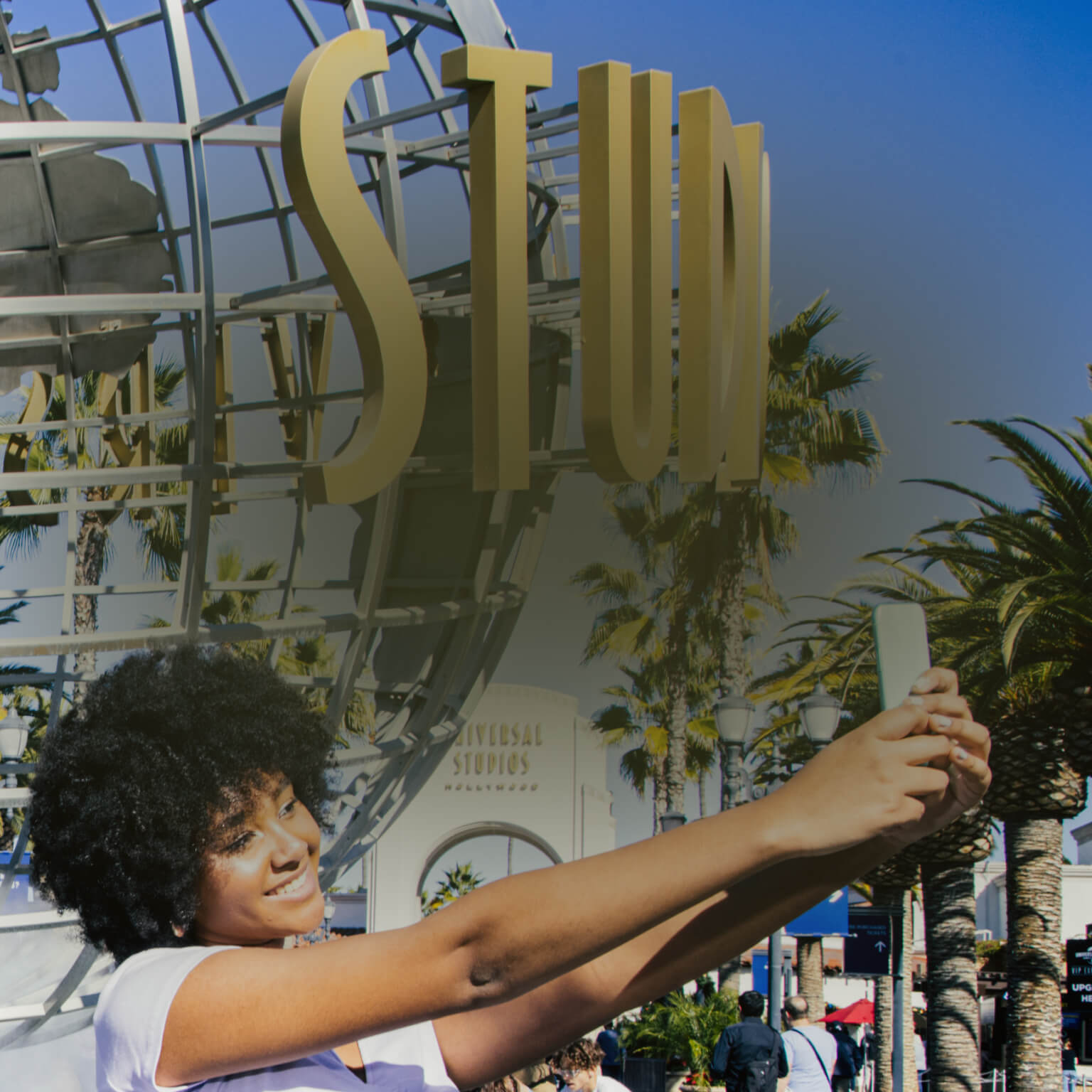 Woman takes a selfie in front of the Universal Studios Globe as people walk by in the background.