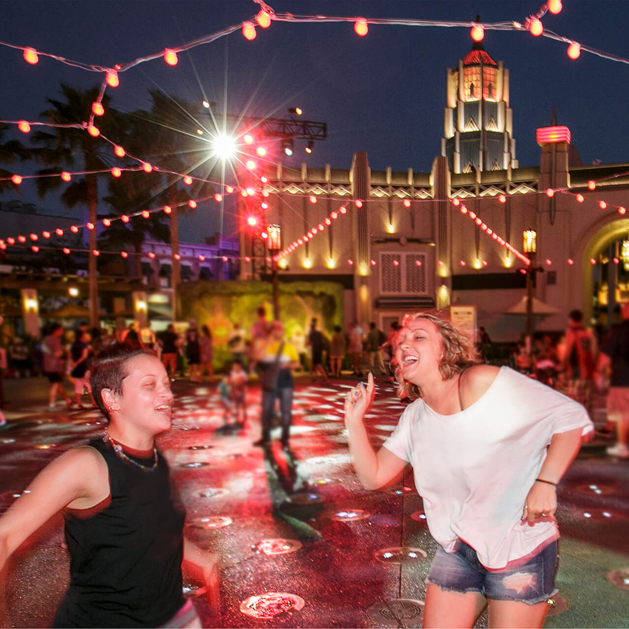 Two guests dancing together under string lights during a nighttime event at Universal Studios Hollywood.