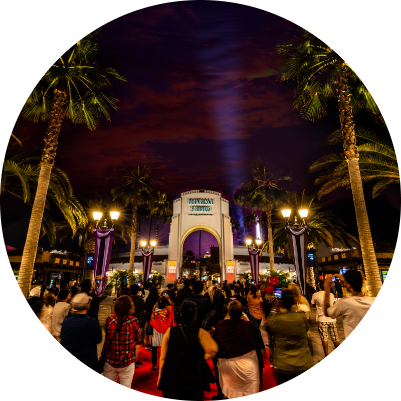 A crowd gathered outside the archway at night for the USH Pass Member Park Takeover presented by Coca-Cola