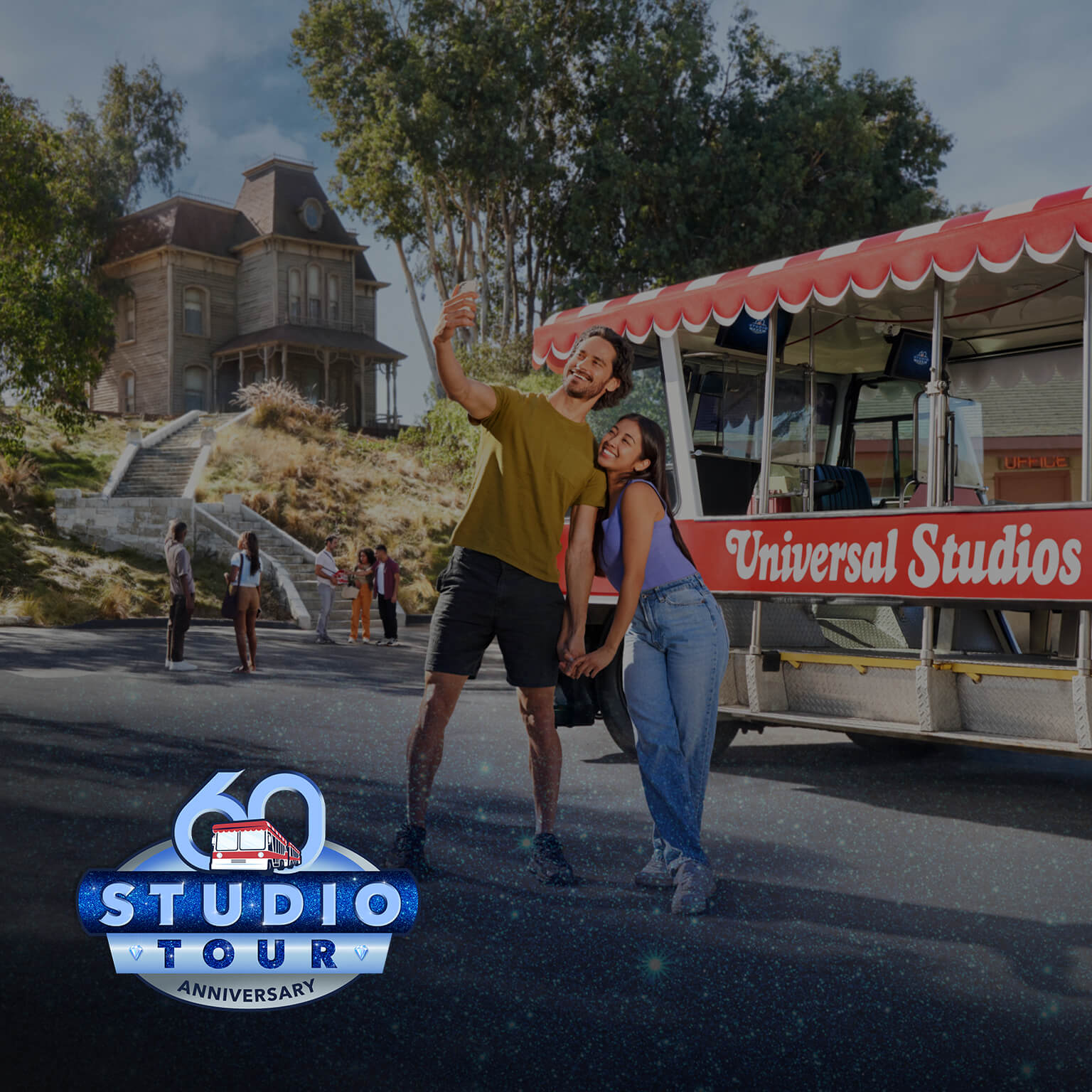 Two people take a selfie in front of the tram during Studio Tour’s 60th anniversary at Universal Studios Hollywood.