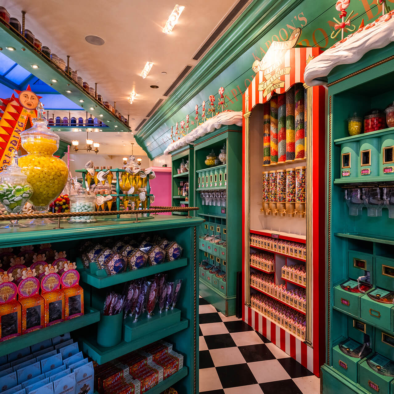 A countertop of candy llled kars and a wall display of various desserts inside Honeydukes™ at Universal Studios Hollywood.